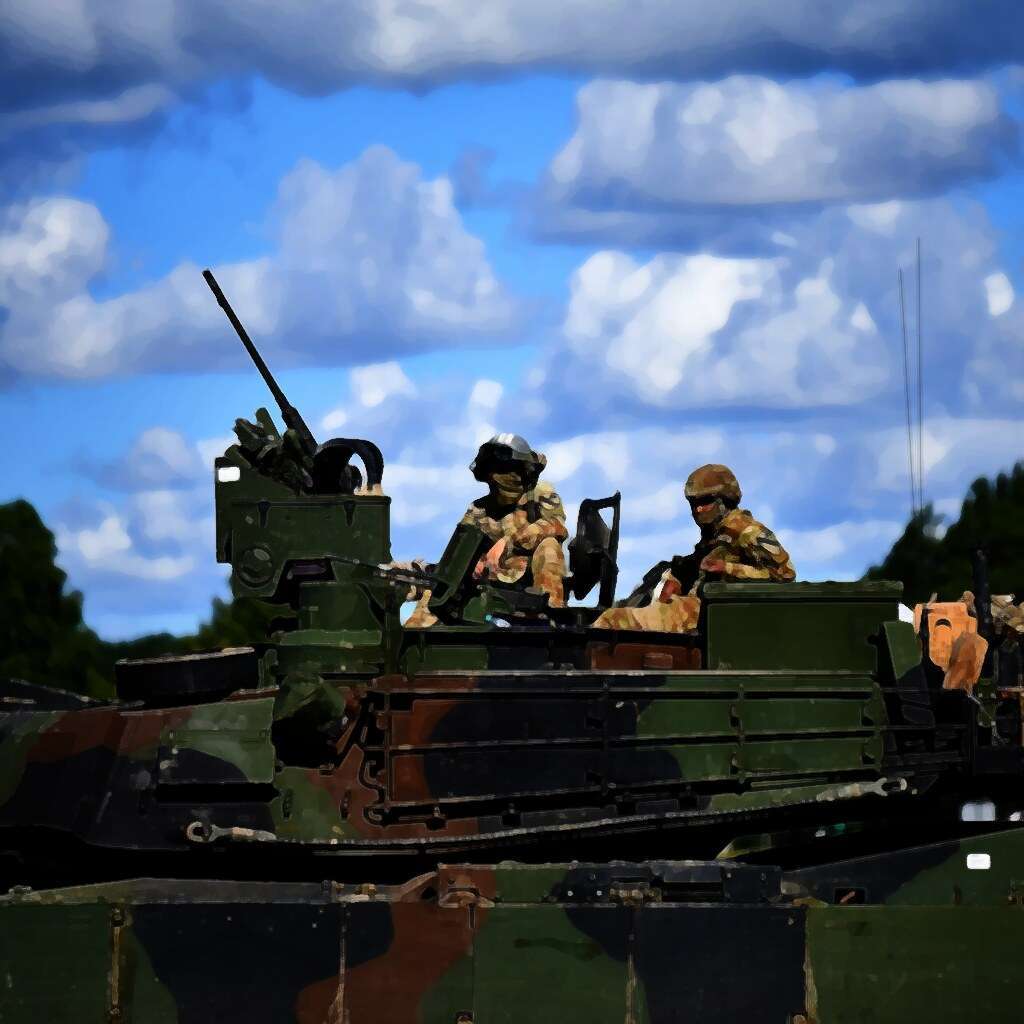 Two soldiers on top of a camouflaged armoured vehicle during a military exercise, with forest and a blue sky behind them